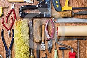 Tools for repair: roller, chisel, pliers, glass cutter, hammer on a wooden background