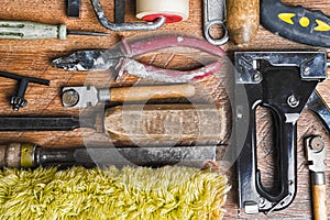 Tools for repair: roller, chisel, pliers, glass cutter on a wooden background