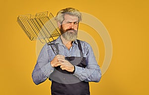 Tools for roasting meat. Man in apron hold barbecue grill. Chef cooking bbq food. Summer picnic. Hipster dyed beard