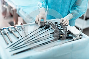 Doctor in sterile gloves taking laparoscopic instrument photo