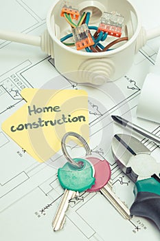 Tools using for works, home keys, electric box with connected colorful cables and diagrams of plan with electrical installation.