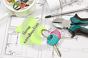 Tools using for works, home keys, electric box with connected colorful cables and diagrams of plan with electrical installation.