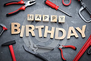 Tools and words HAPPY BIRTHDAY on stone background, flat lay