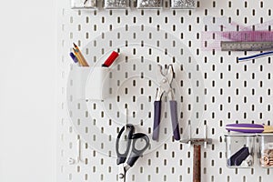 tools for working in the sewing workshop scissors, a needle case with needles hanging on a peg board, as an idea for