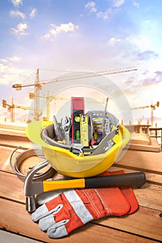 Tools in a yellow helmet on a construction site with a background crane