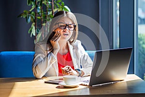 Tooth ache. Portrait of sad sick beautiful stylish brunette young woman in glasses sitting, touching her cheek, because feeling