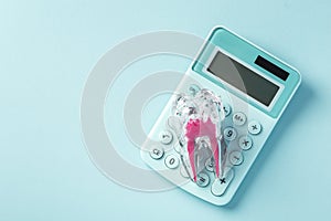 Tooth with calculator on blue background, dental cost and insurance