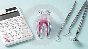 Tooth with calculator and dentist tools on blue background, dental cost