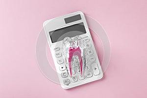 Tooth with calculator on pink background, dental cost and insurance