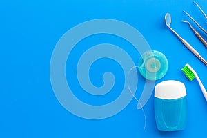 Tooth care with toothbrush, dental floss and dentist instruments. Set of cleaning products for teeth on blue background