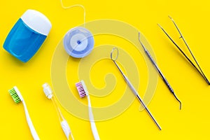 Tooth care with toothbrush, dental floss and dentist instruments. Set of cleaning products for teeth on yellow