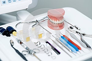 Tooth model with metal braces lying on a dental table with instruments