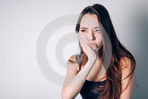 Tooth pain, dentistry. Beautiful young woman suffering from terrible strong teeth pain, touching cheek with hand.