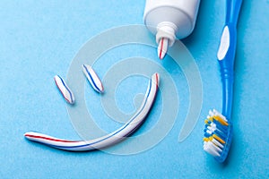 Tooth-paste in the form of a face with a smile. Tube of toothpaste and toothbrush on a blue background