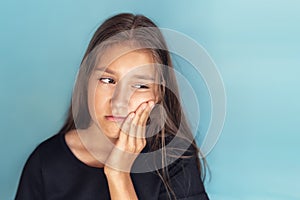 Tooth Sensitivity Concept. Unhappy asian girl suffering from toothache, touching cheek, blue studio wall, copy space