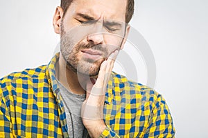 Toothache. Handsome young man suffering from toothache, closeup, touching his cheek to stop pain against white background