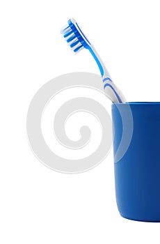 Toothbrush in blue plastic cup isolated over white background