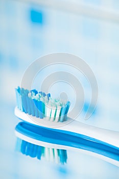 Toothbrush on blue tile background with mirror reflection