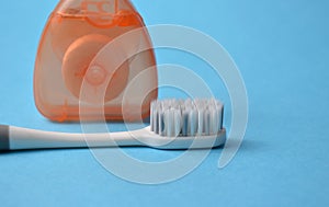 Toothbrush and dental floss on a blue background.