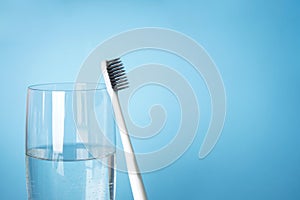 Toothbrush and a glass of water, close-up with space for text on a blue background