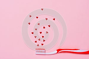 Toothbrush and heart shape candies on pink background