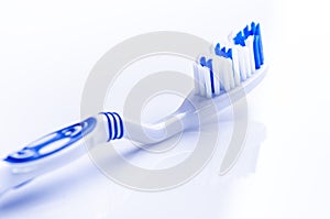 Toothbrush isolated on a white background with reflection and toothpaste. Blue plastic toothbrush. Concept of dental medicine.