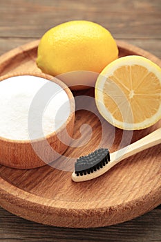 Toothbrush with lemon and baking soda on grey wooden background. Vertical photo