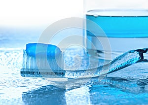 Toothbrush and mouthwash on wet glass