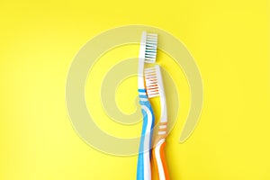 Toothbrush sparing another toothbrush on a yellow background.