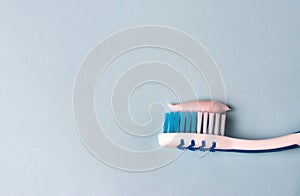 Toothbrush with toothpaste on a blue background, close-up, teeth care concept, copy space