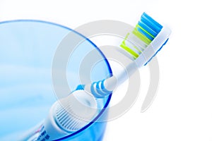 Toothbrush and toothpaste in blue plastic glass