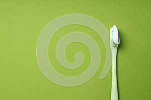 Toothbrush with toothpaste on green background, space for text