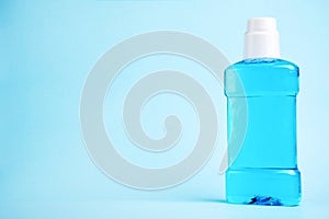 A toothbrush with toothpaste and mouthwash on blue background