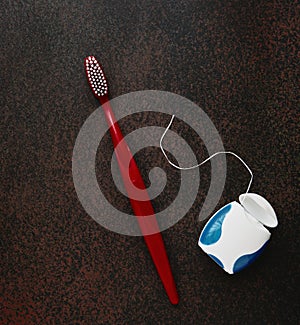Toothbrushe and dental floss on dark background close up, with copy space