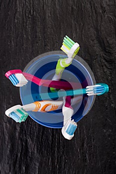 Toothbrushes in a blue plastic glass on black stone background