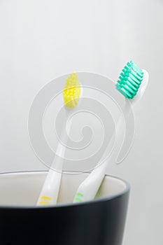 Toothbrushes in cup on white background