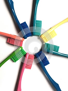 Toothbrushes of various colors arranged in a star shape on a white background.