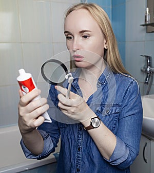 Toothpaste ingredients. Girl checks composition of toothpaste and is surprised by dangerous composition of product. Emulsifiers,