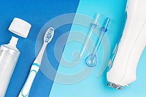 Toothpaste, toothbrush and dental irrigator on blue background