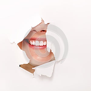 Toothy smile of cheerful teen girl through hole of white