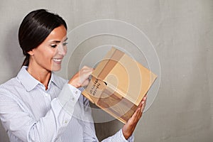 Toothy smile woman standing and opening parcel