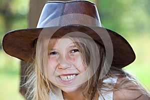 Toothy smile of young pretty girl in cowboy hat, facial portrait