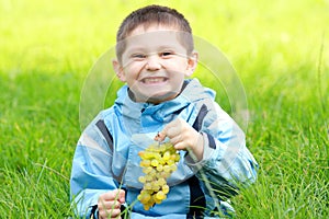 Toothy smiling boy with grapes