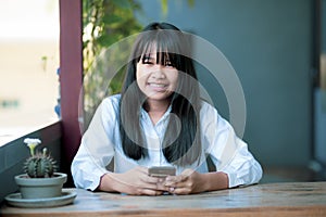 Toothy smiling face of asian teenager with smart phone in hand