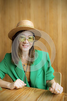 Toothy smiling face of asian woman wearing green suit standing against yellow background