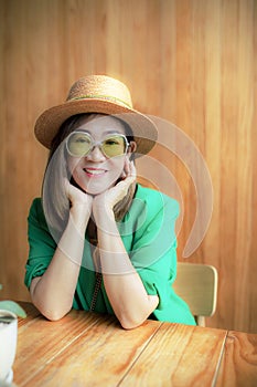 Toothy smiling face of asian woman wearing green suit standing against yellow background