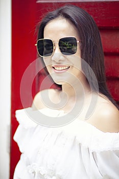 Toothy smiling face of beautiful asian younger woman wearing sunglasses