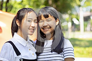 Toothy smiling face of two asian teenager standing outdoor