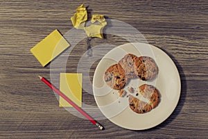 Top above close up overhead view photo of tasty homemade cookies broken bitten biscuits on white round plate with crumbled paper s