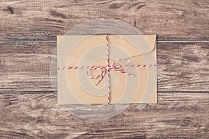 Top above close up photo image of old craft envelope tied up with striped string on wood timber backdrop